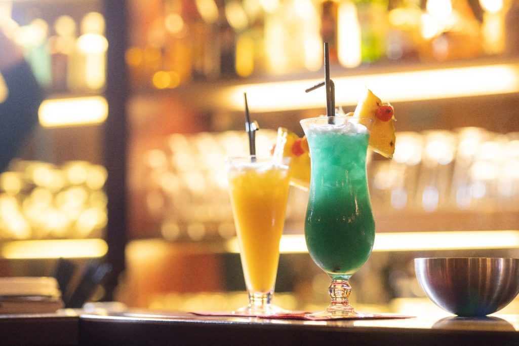 Zwei farbenfrohe Cocktails in Gläsern auf der Bar Mákaá